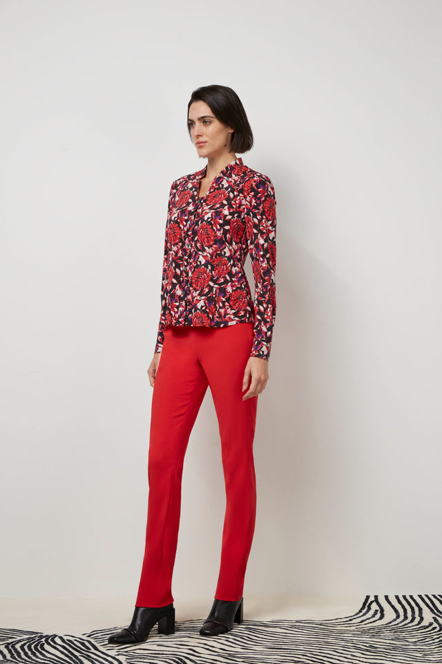 Side profile of a woman wearing a red 'Bard' blouse and red 'Cremisi' trousers