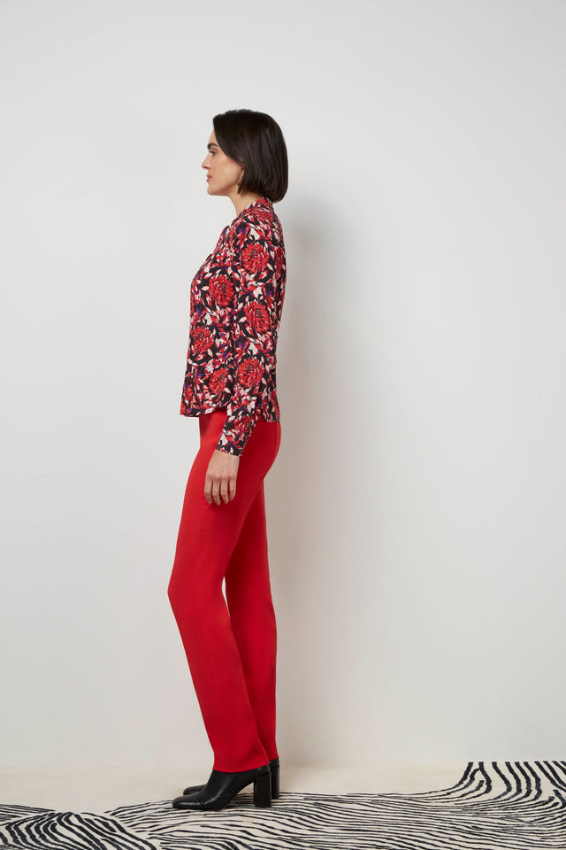 Side profile of a woman wearing a red 'Bard' blouse and red 'Cremisi' trousers