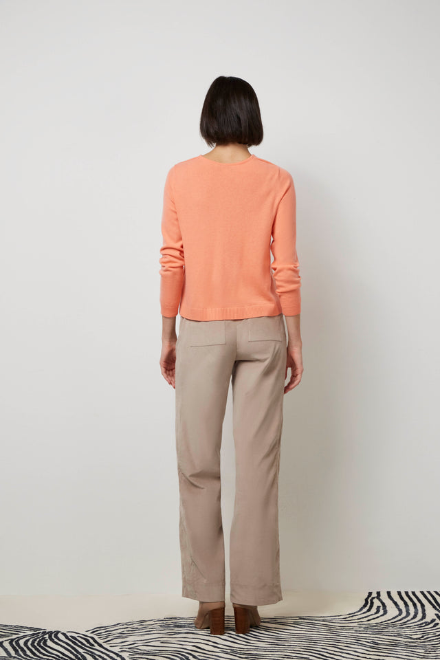 Back of a woman wearing a coral 'Musical' knit pullover