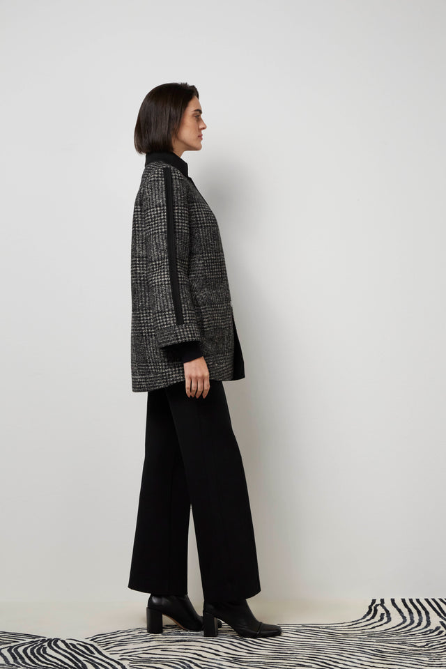 Side profile of a woman wearing the outside of a black 'Lara' knit coat