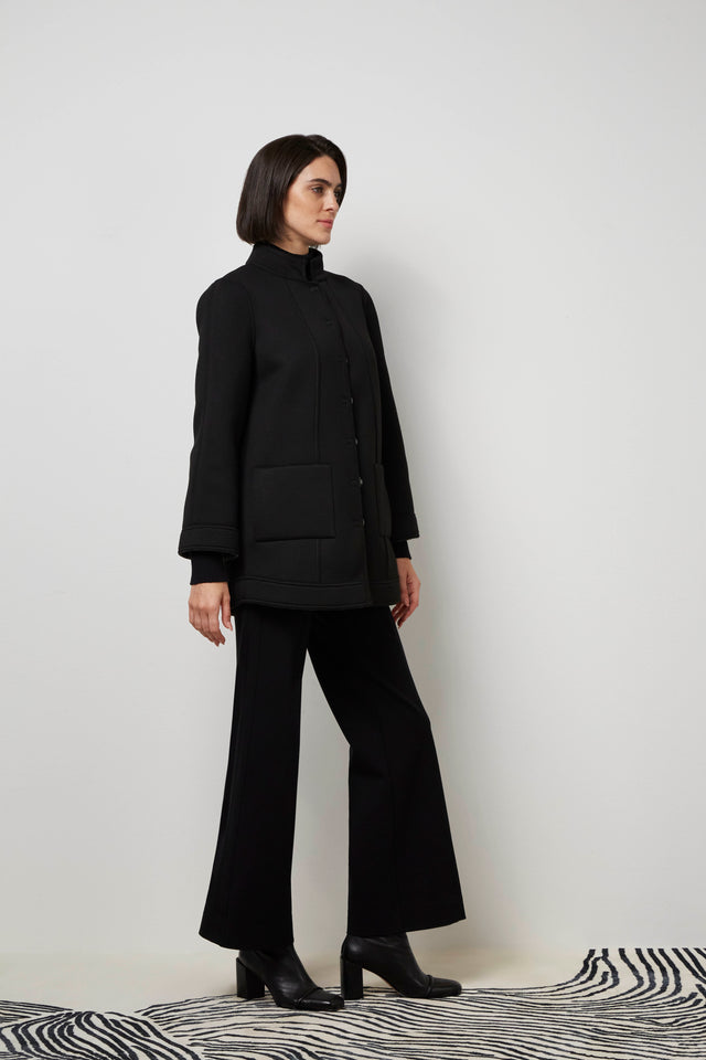 Side profile of a woman wearing the inside of a black 'Lara' knit coat